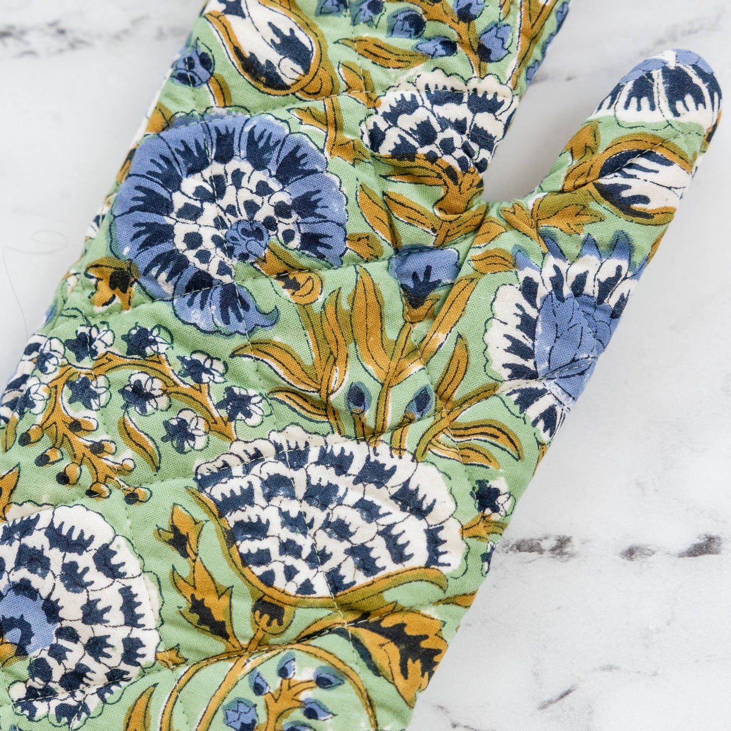 Floral patterned oven mitt on a marble surface