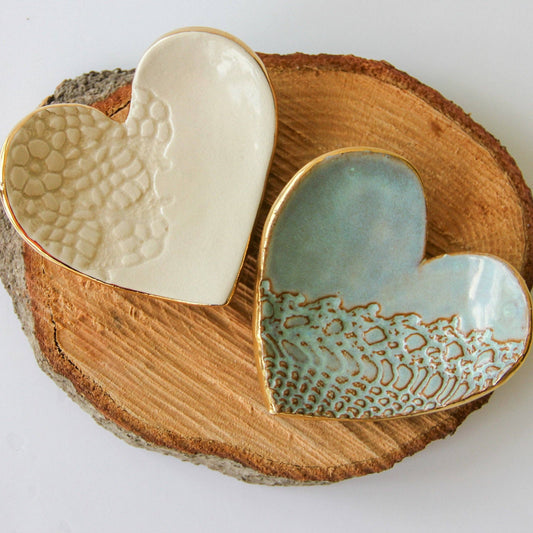 two ceramic heart rings with lace pattern on round wood board