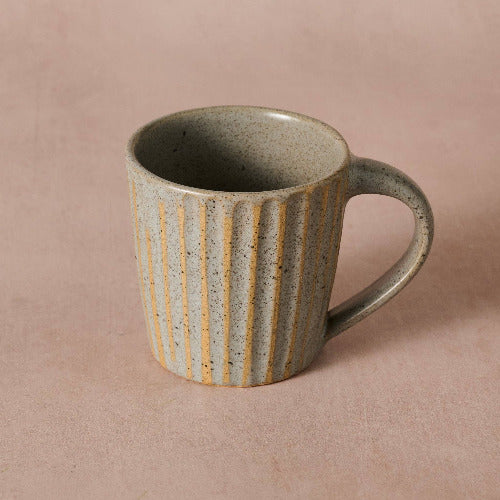 Ceramic mug with striped design on a beige background