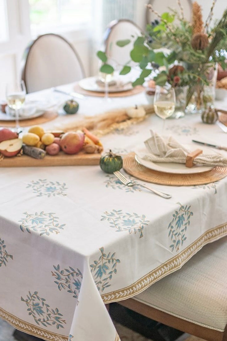 white plate, serving utensils and succulent plant overlayed on a white runner with blue and green pattern