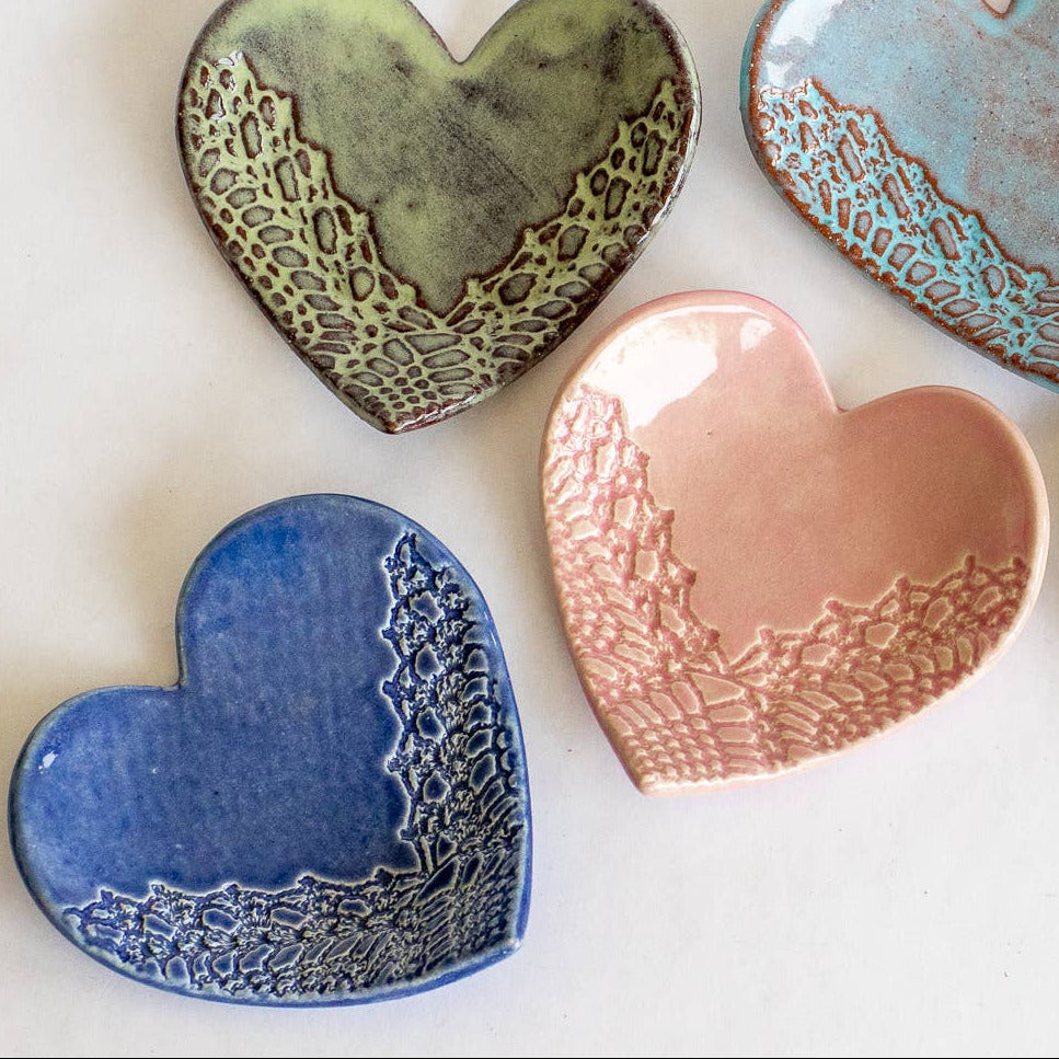 Set of handmade heart-shaped ceramic plates in various colors on a white background