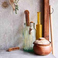 Vintage bottles and a wooden jar on a textured surface with a neutral background with all natural brushed inside the bottle