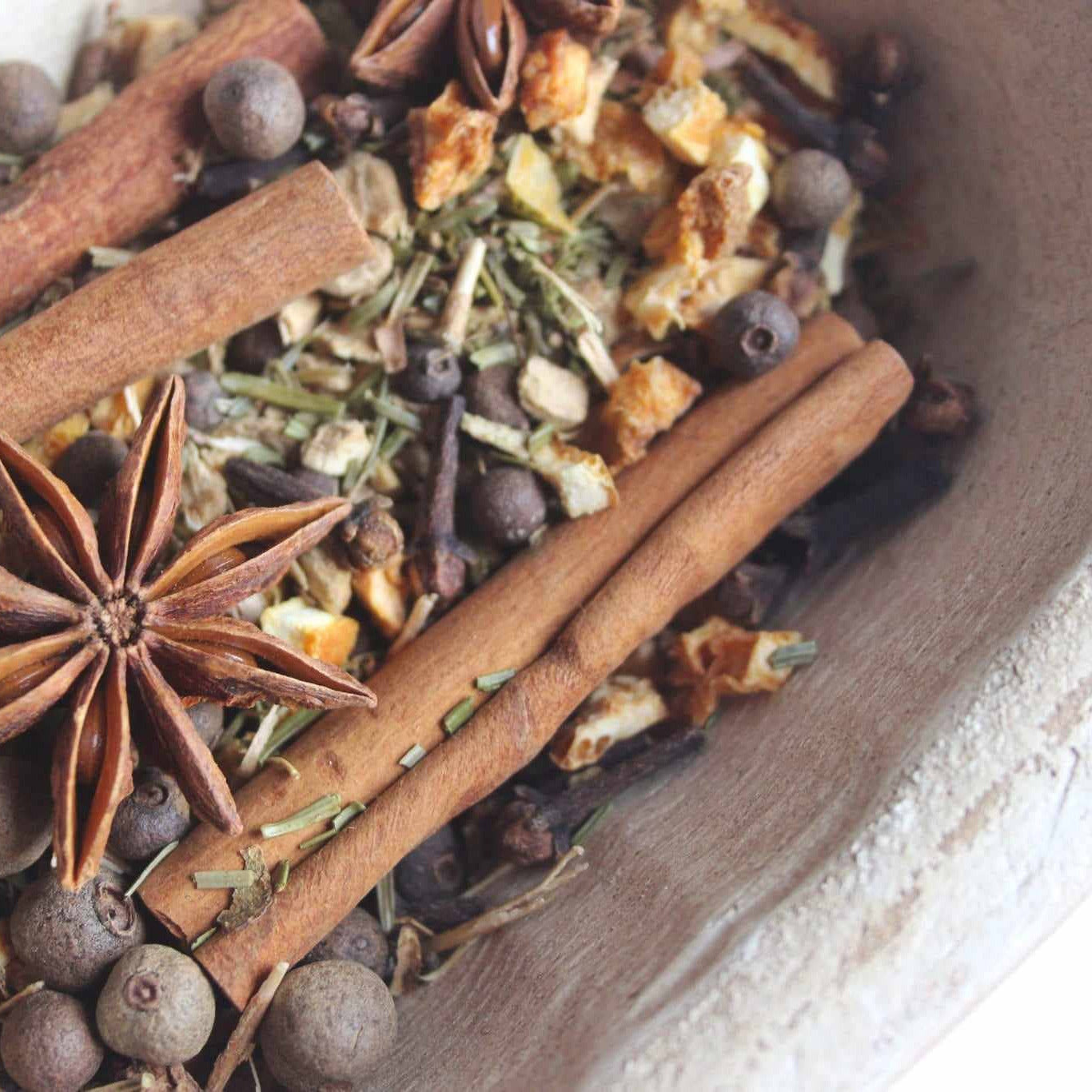Potpourri spices including cinnamon sticks, star anise, and peppercorns in a bowl.