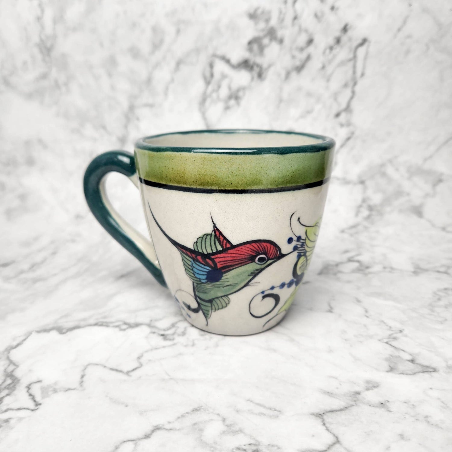 Ceramic mug with a colorful hummingbird design on a marble surface