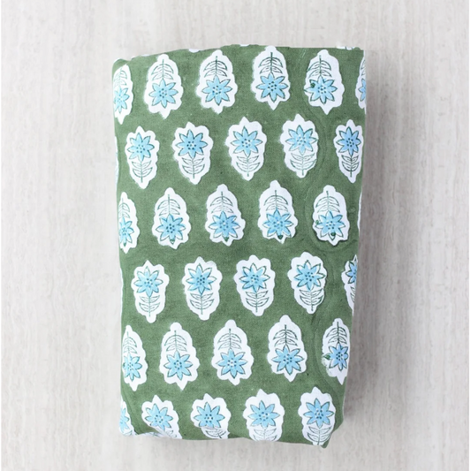 Sage block print table clothe with blue floral patterns folded on a white background