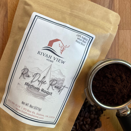 Rivah View Home Rio Dulce Roast coffee package with coffee beans and a scoop on a wooden surface