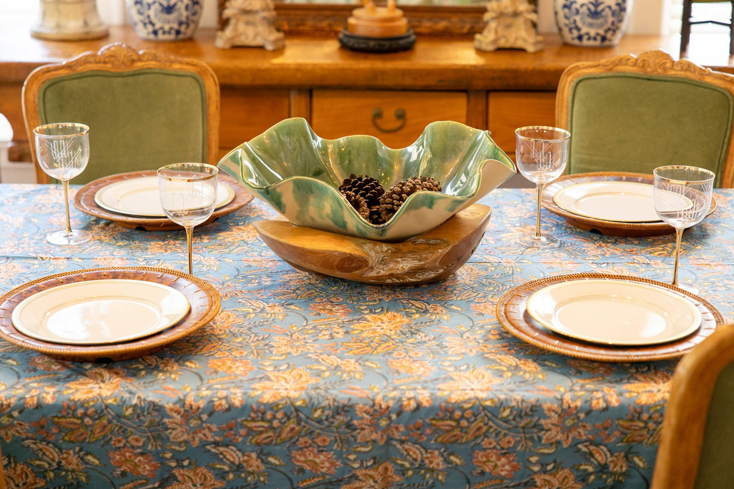 Dining table set with plates, bowls, and glasses on a handblocked tablecloth.