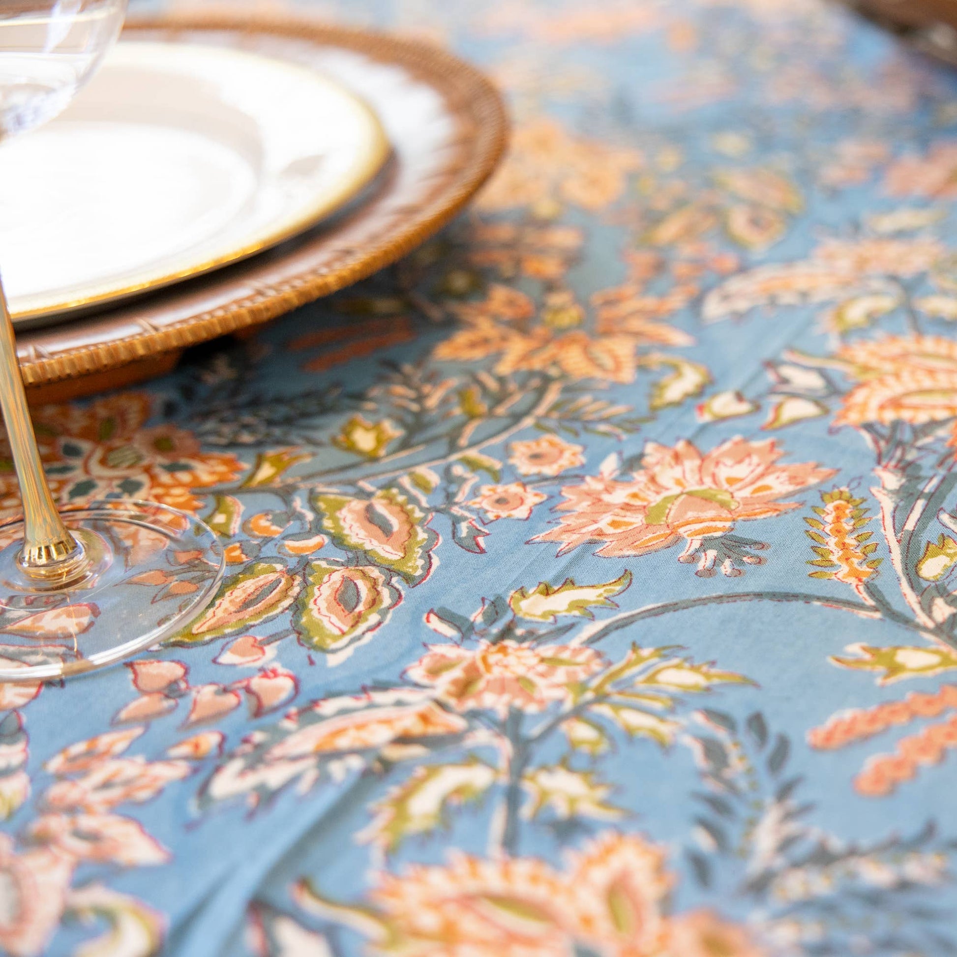Floral patterned hand blocked tablecloth on a table with decorative items.