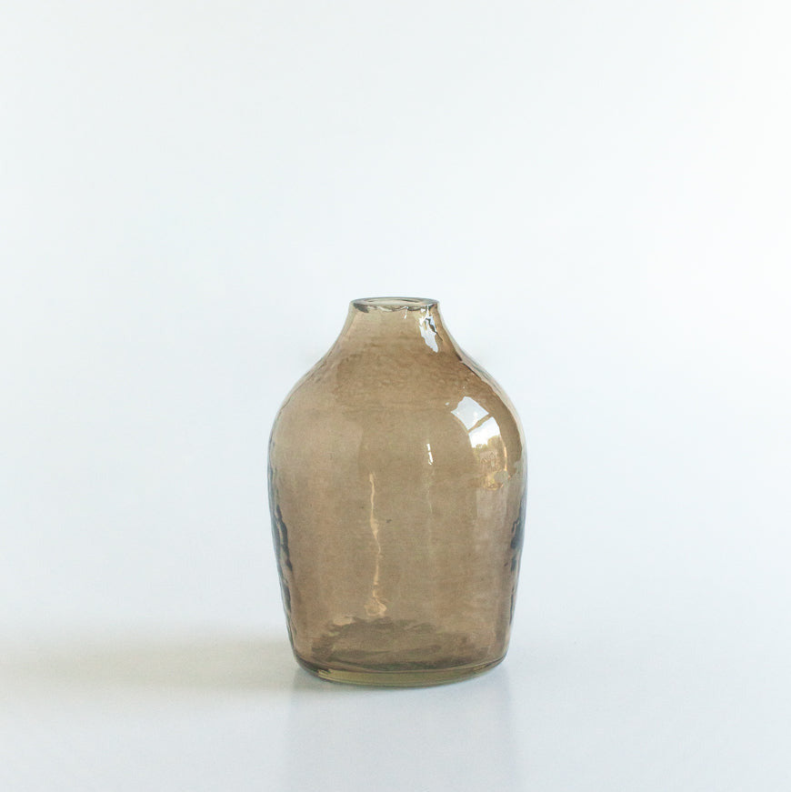 Smoky handblown hammered glass bud vase on a white background