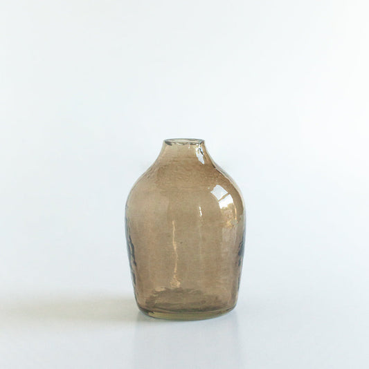 Smoky handblown hammered glass bud vase on a white background