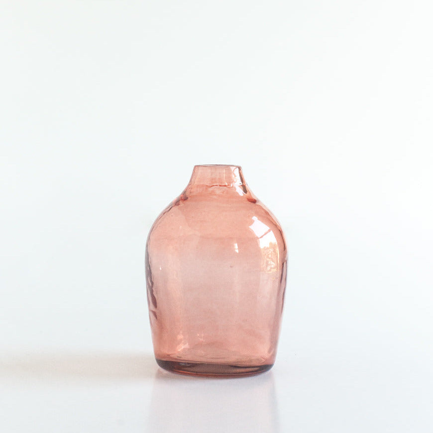 Pink handblown hammered glass bud vase on a white background