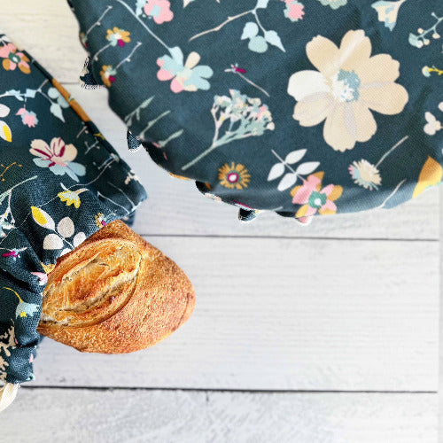 Floral-patterned fabric bowl cover and bread bag with a bun on a wooden surface