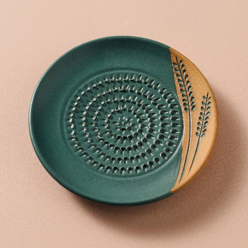 Ceramic grater with green and beige design on a beige background