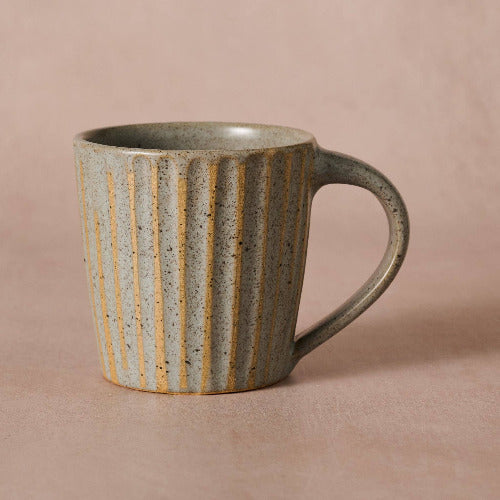 Ceramic mug with striped design on a beige background