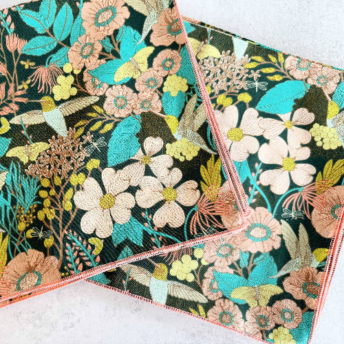 Two floral hummingbird-patterned cocktail napkins on a light background