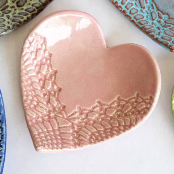 Set of handmade heart-shaped ceramic plates in various colors on a white background
