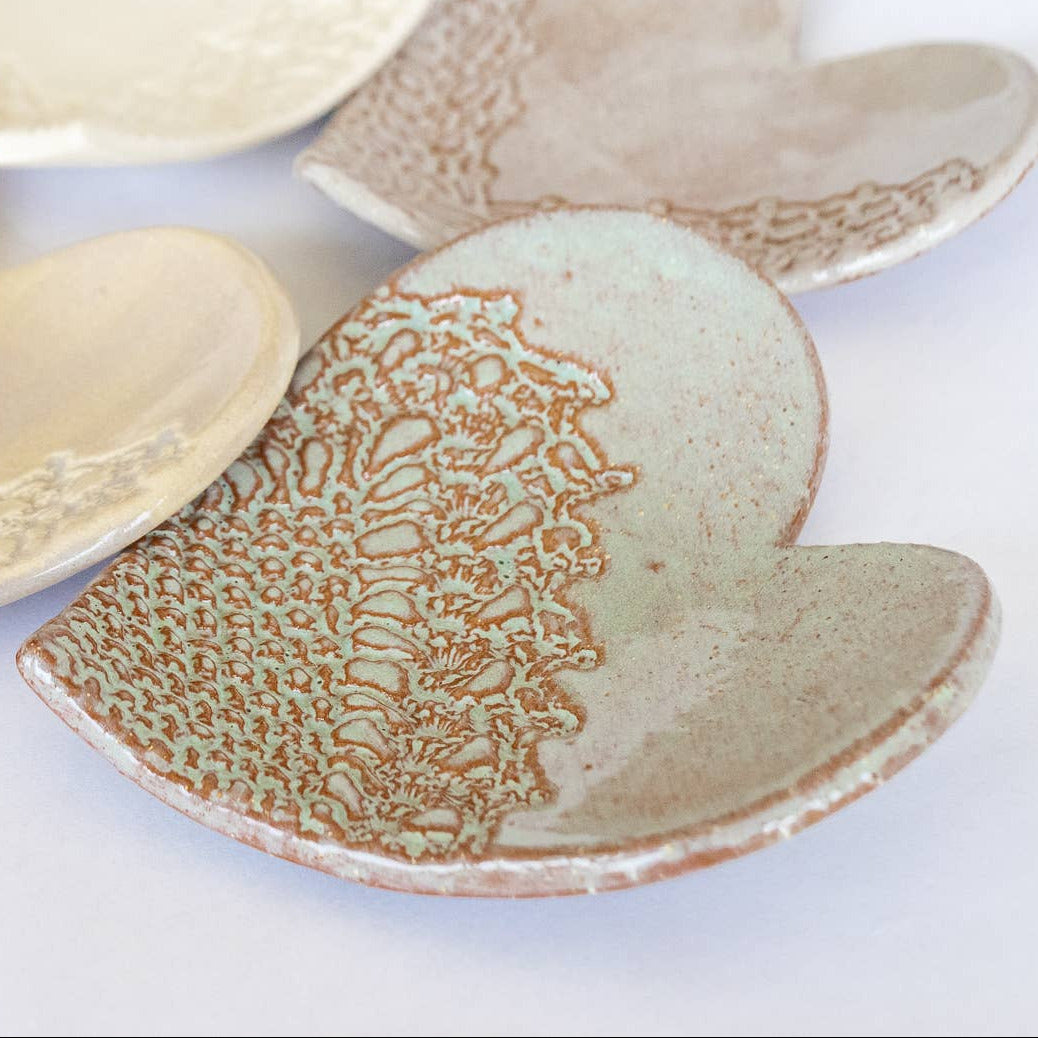 Set of ceramic handmade heart-shaped plates with textured surfaces on a white background