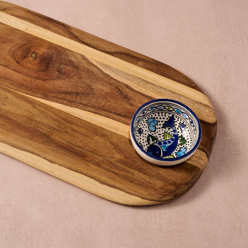 Wooden cutting board with a ceramic bowl featuring blue and white patterns on a beige background