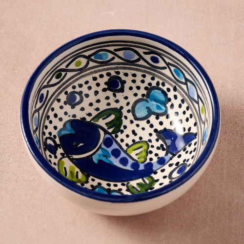 Ceramic bowl with fish design on a beige background