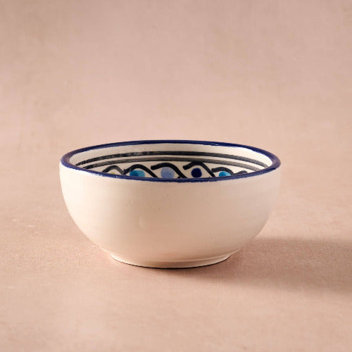 White ceramic bowl with blue decorative rim on a beige background