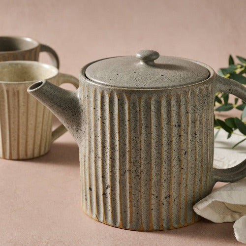 Ceramic teapot with ribbed design on a pink surface