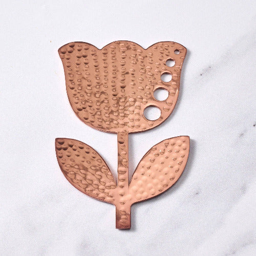 Copper tulip-shaped herb stripper on a white marble surface