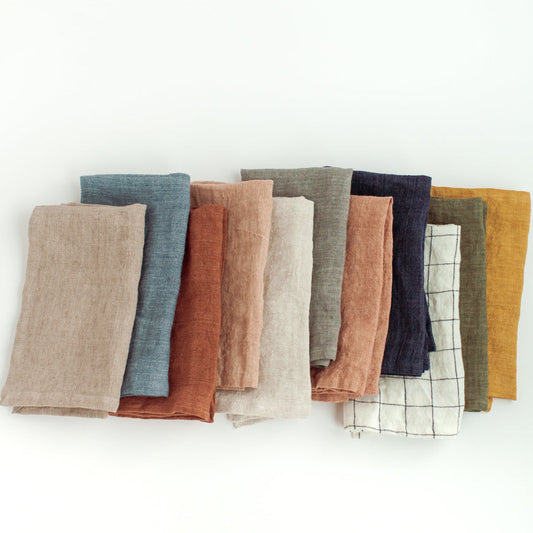 Set of folded fabric napkins in various colors on a white background